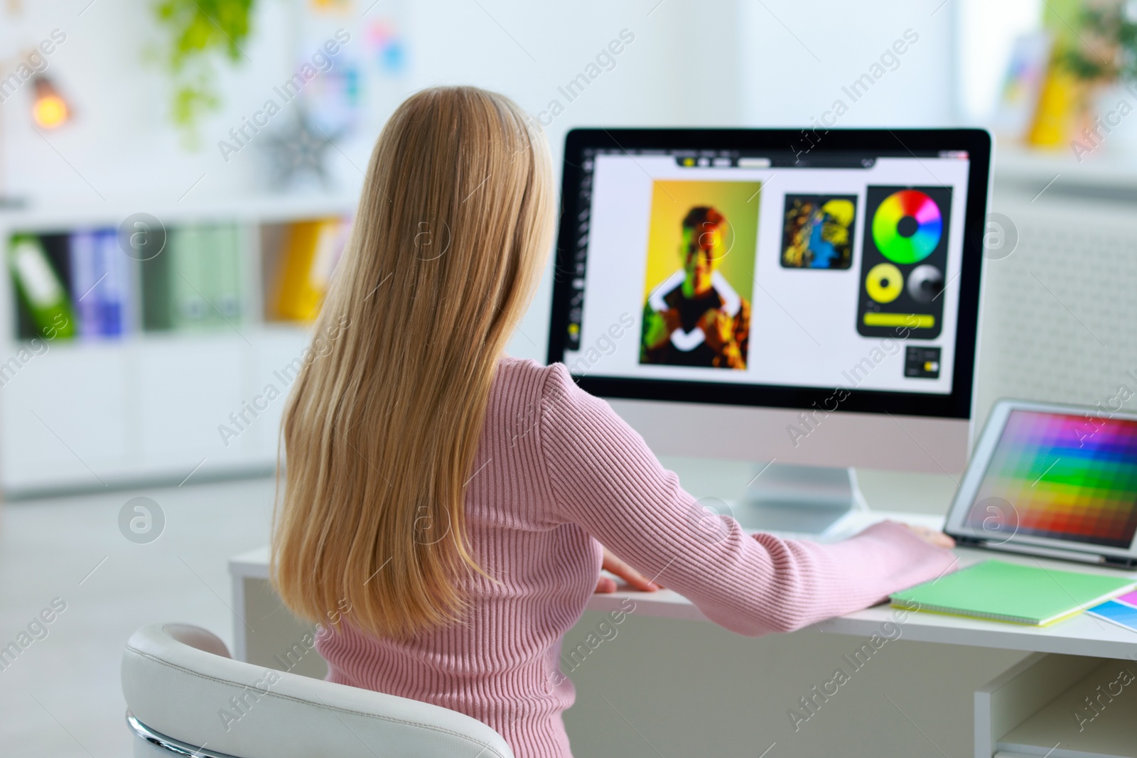 Photo of Graphic designer working with computer at table in office, back view