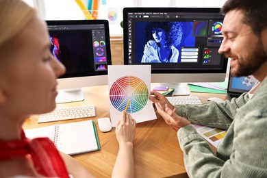 Designers with color palette working together at table in office