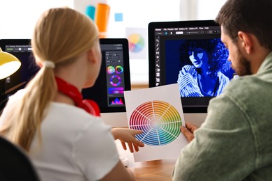 Designers with color palette working together at table in office, back view