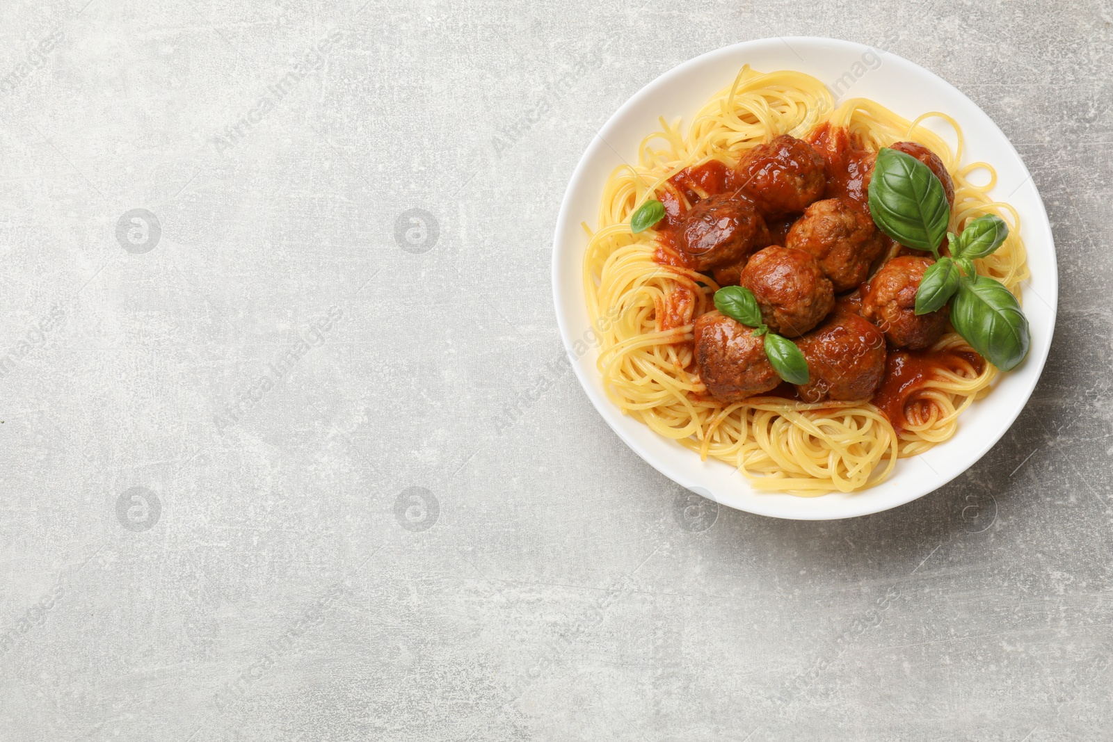 Photo of Delicious pasta with meatballs on grey table, top view. Space for text