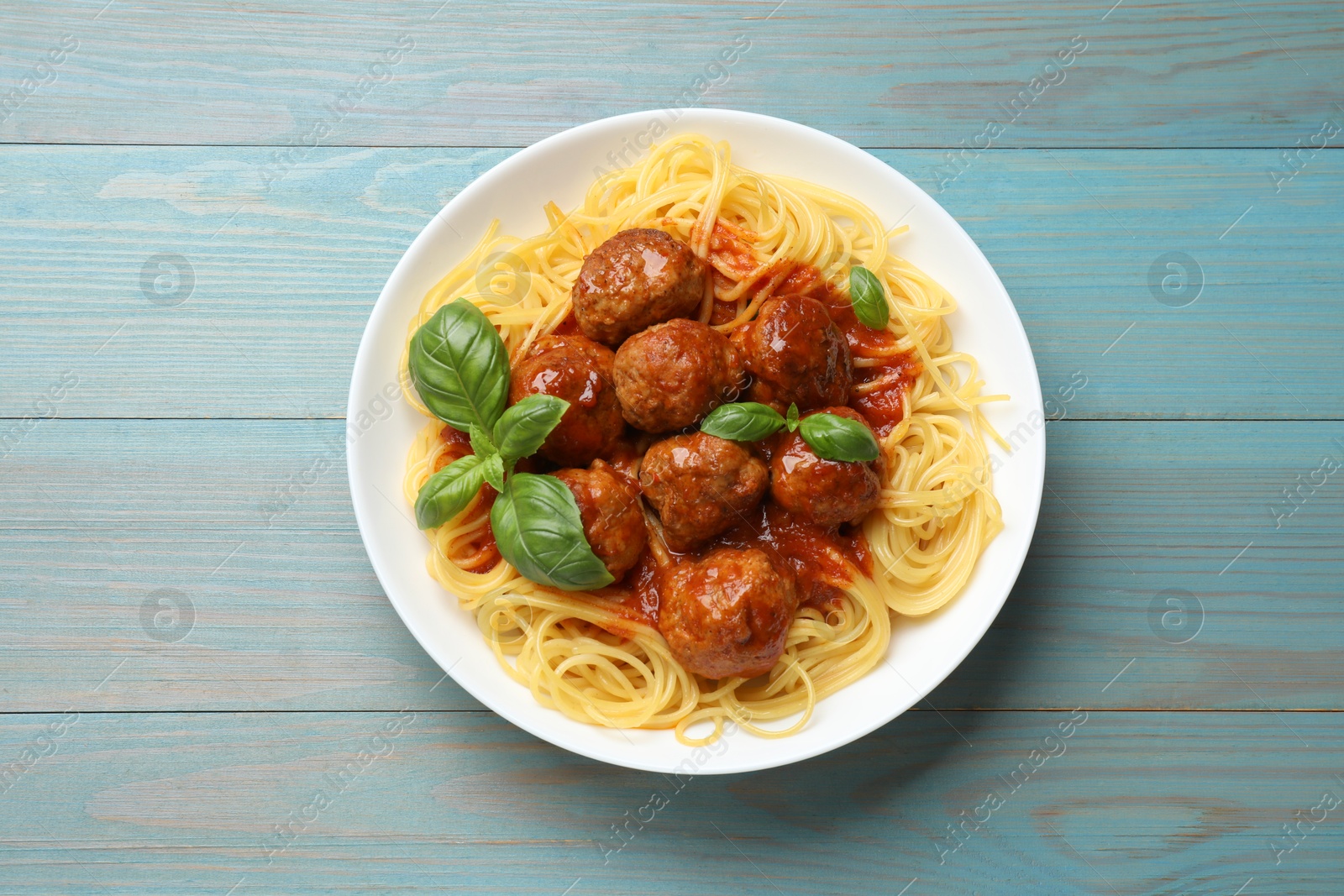 Photo of Delicious pasta with meatballs on blue wooden table, top view