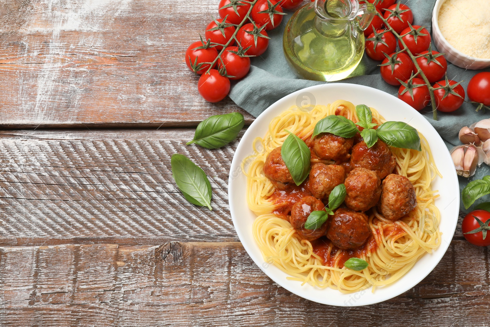 Photo of Delicious pasta with meatballs and ingredients on wooden table, flat lay. Space for text