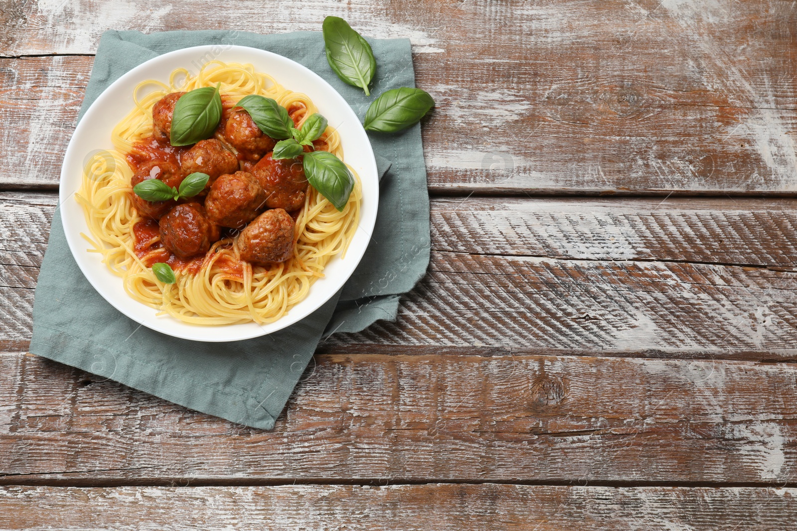 Photo of Delicious pasta with meatballs on wooden table, top view. Space for text