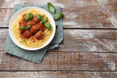 Photo of Delicious pasta with meatballs on wooden table, top view. Space for text