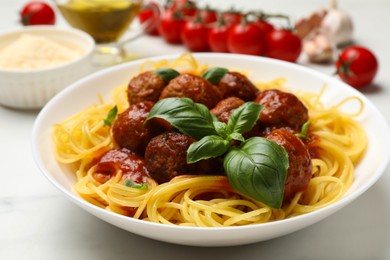 Photo of Delicious pasta with meatballs and ingredients on white marble table, closeup