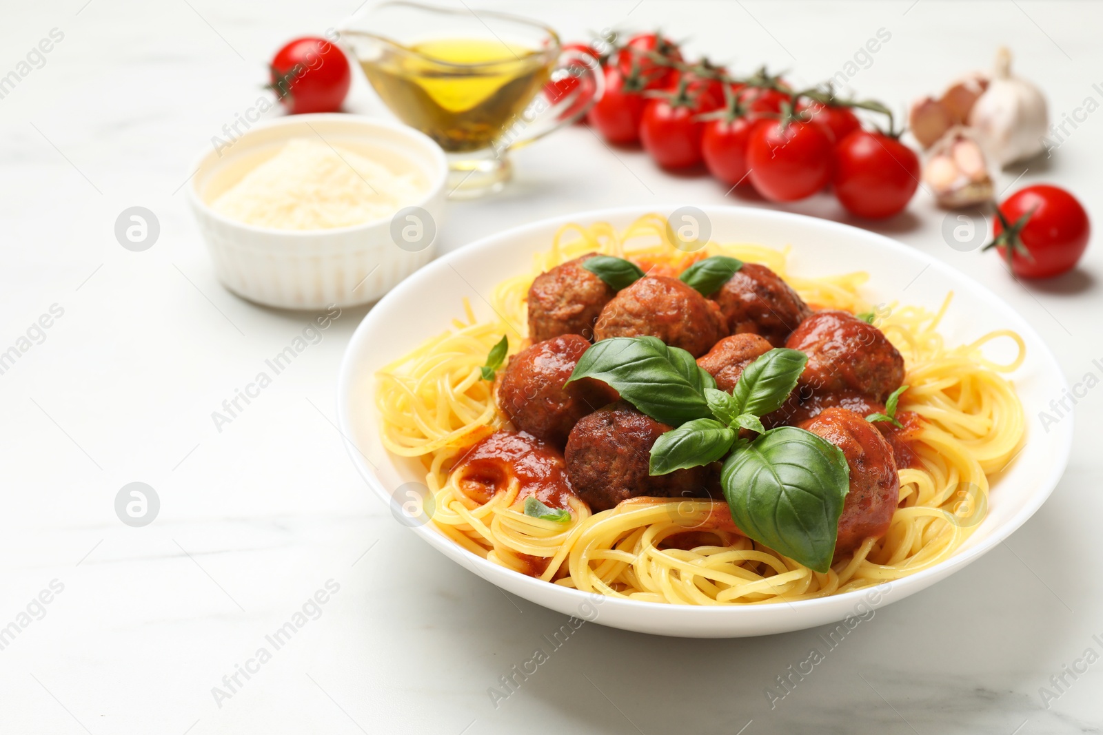 Photo of Delicious pasta with meatballs and ingredients on white marble table