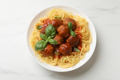 Photo of Delicious pasta with meatballs on white marble table, top view