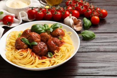 Photo of Delicious pasta with meatballs and ingredients on wooden table, closeup