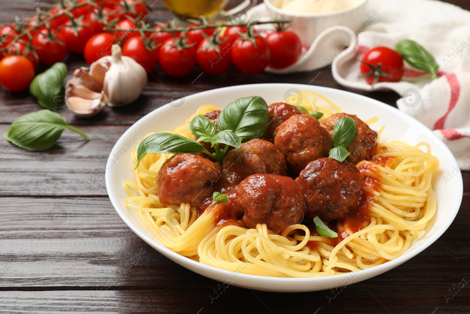 Photo of Delicious pasta with meatballs and ingredients on wooden table, closeup