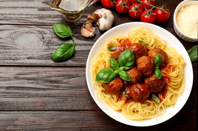 Photo of Delicious pasta with meatballs and ingredients on wooden table, flat lay