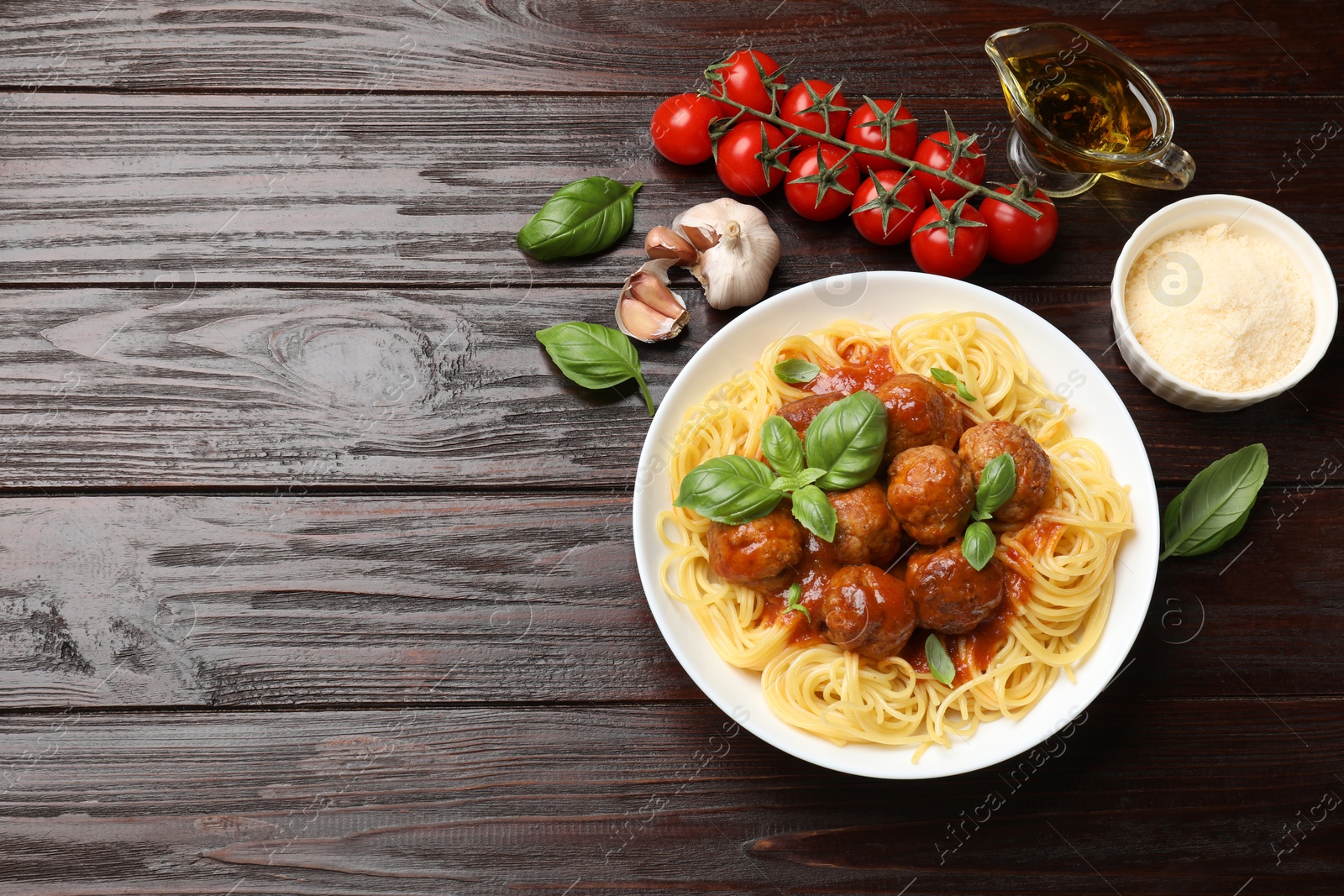 Photo of Delicious pasta with meatballs and ingredients on wooden table, flat lay. Space for text