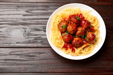 Photo of Delicious pasta with meatballs on wooden table, top view. Space for text