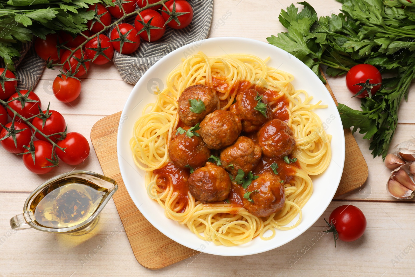 Photo of Delicious pasta with meatballs and ingredients on white wooden table, flat lay