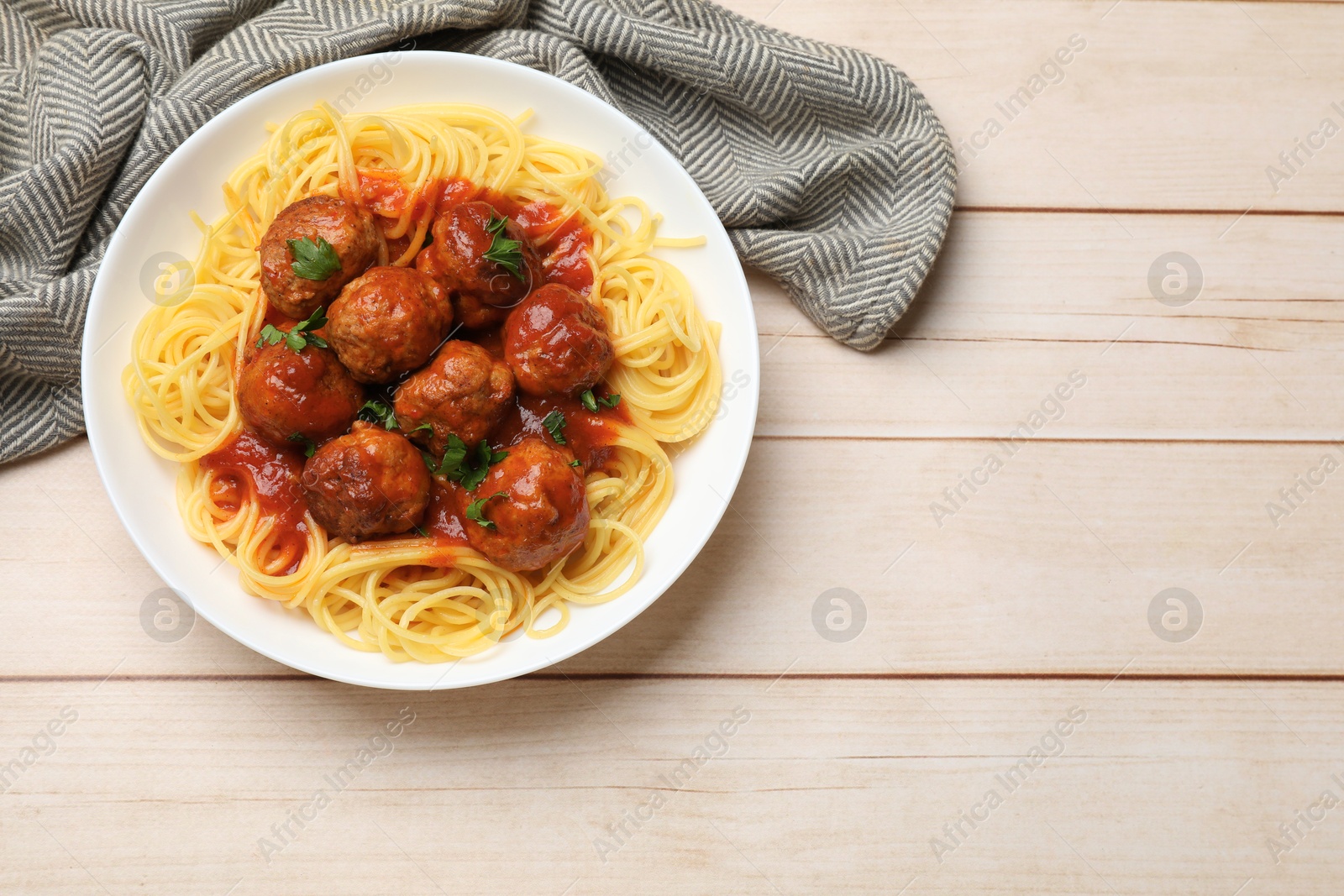 Photo of Delicious pasta with meatballs on white wooden table, top view. Space for text