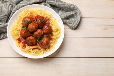 Photo of Delicious pasta with meatballs on white wooden table, top view. Space for text