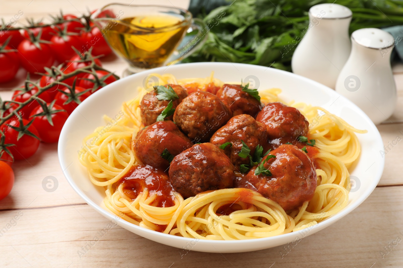 Photo of Delicious pasta with meatballs and ingredients on white wooden table, closeup