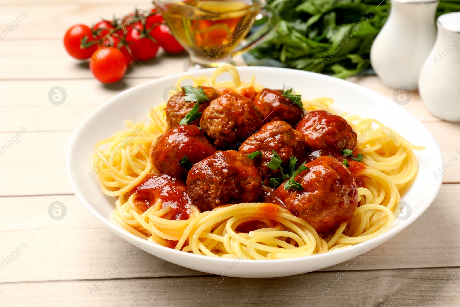 Photo of Delicious pasta with meatballs and ingredients on white wooden table, closeup