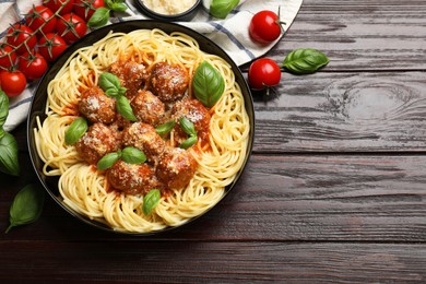 Photo of Delicious pasta with meatballs and ingredients on wooden table, flat lay. Space for text