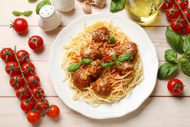 Photo of Delicious pasta with meatballs and ingredients on light wooden table, flat lay