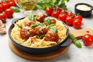 Delicious pasta with meatballs and ingredients on light grey table, closeup