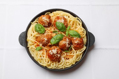 Photo of Delicious pasta with meatballs on white tiled table, top view