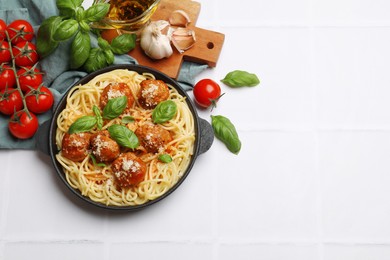 Delicious pasta with meatballs and ingredients on white tiled table, flat lay. Space for text