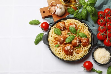 Photo of Delicious pasta with meatballs and ingredients on white tiled table, flat lay. Space for text