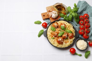 Delicious pasta with meatballs and ingredients on white tiled table, flat lay. Space for text