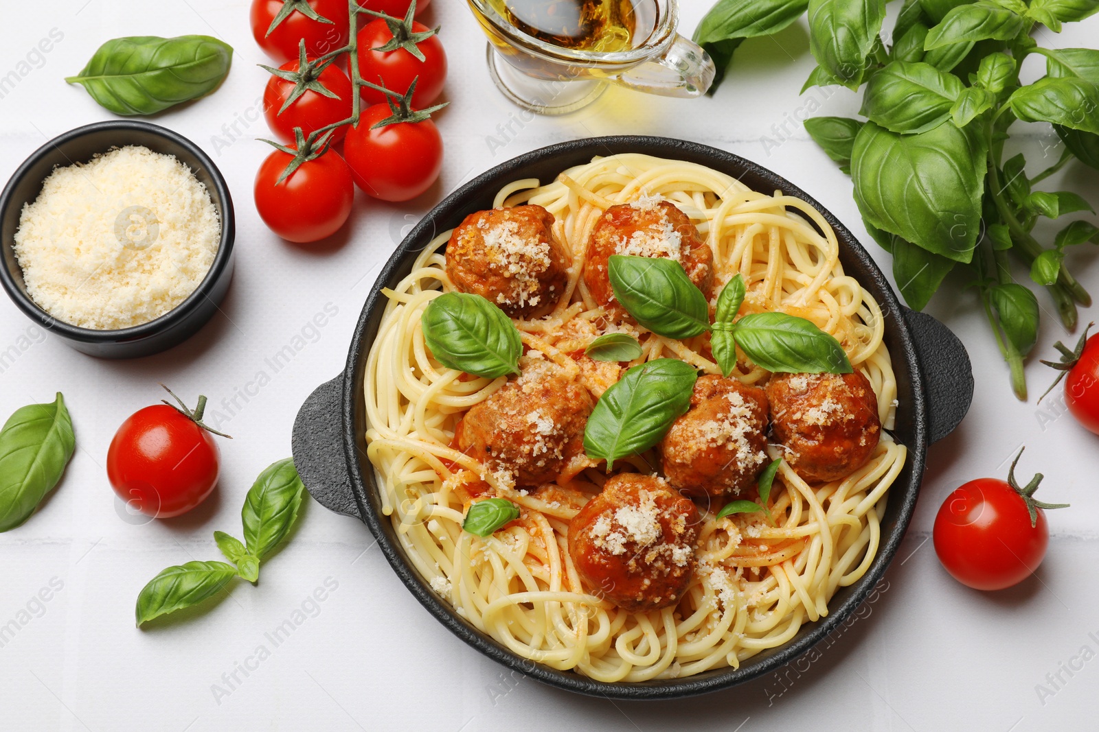 Photo of Delicious pasta with meatballs and ingredients on white tiled table, flat lay