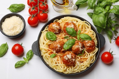 Delicious pasta with meatballs and ingredients on white tiled table, flat lay