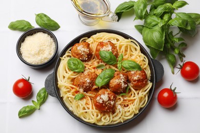 Delicious pasta with meatballs and ingredients on white tiled table, flat lay