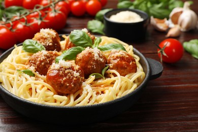 Delicious pasta with meatballs and ingredients on wooden table, closeup