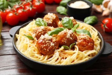 Delicious pasta with meatballs and ingredients on wooden table, closeup