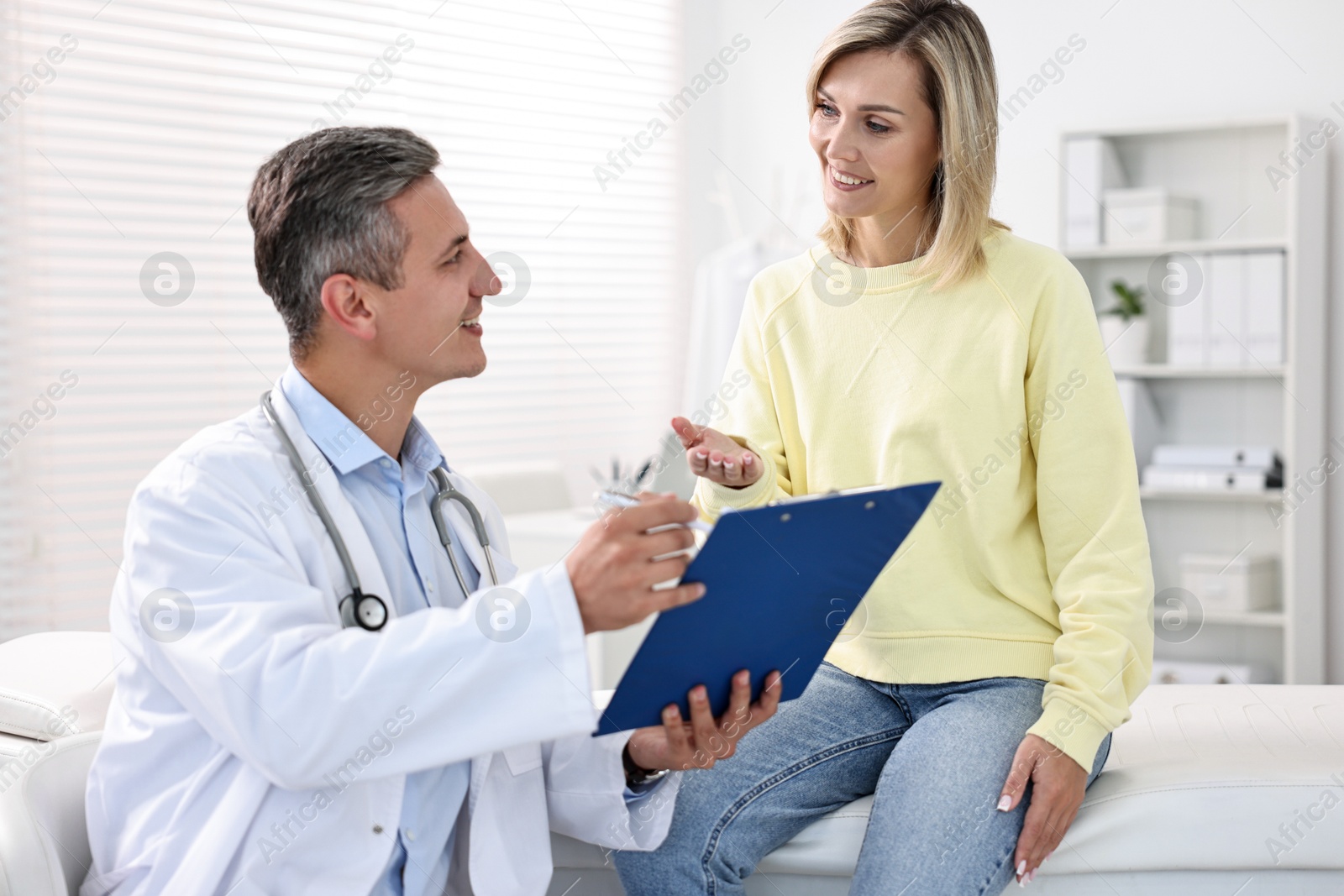 Photo of Healthcare worker with clipboard and patient in hospital