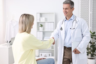 Healthcare worker shaking hands with patient in hospital