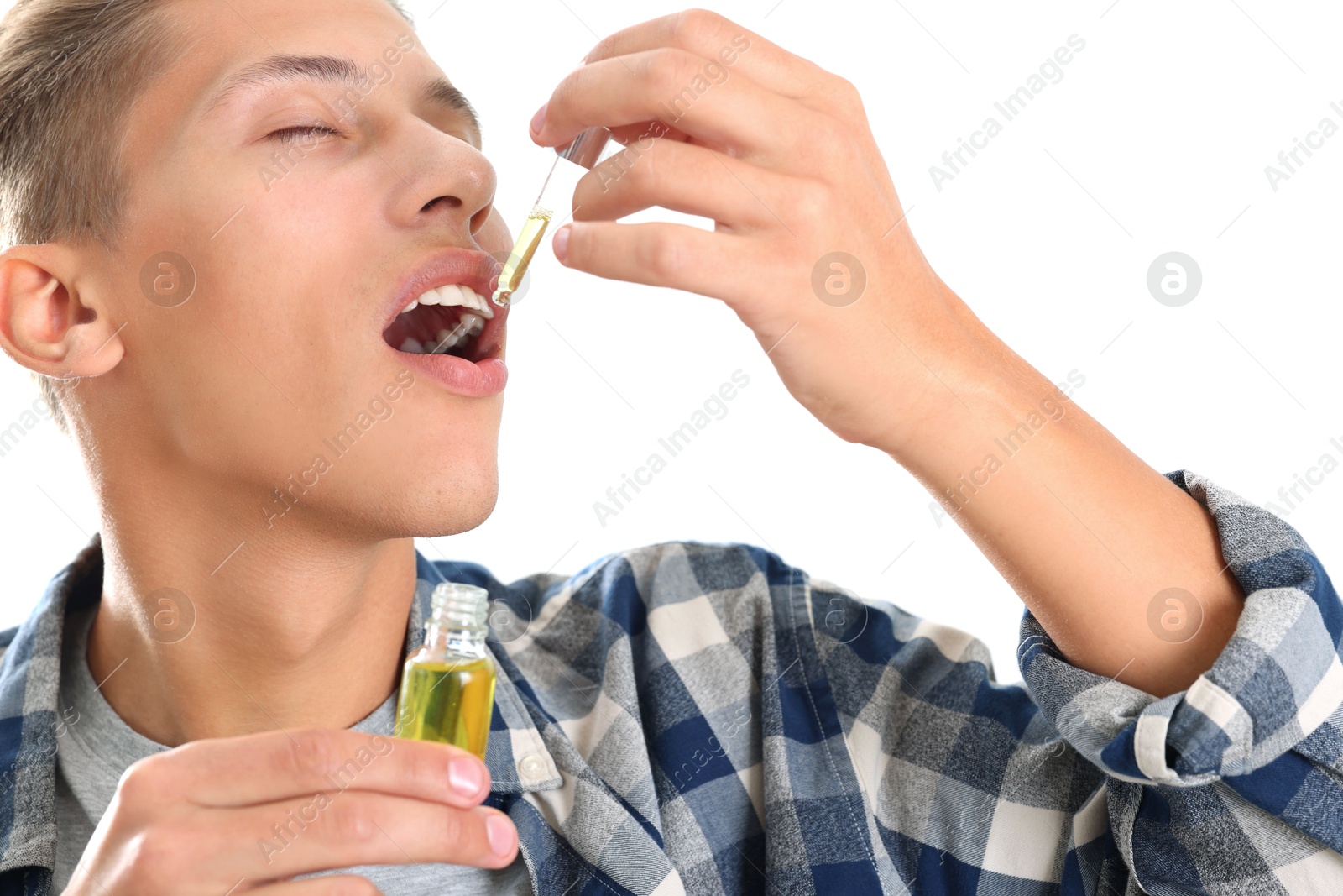 Photo of Young man taking CBD tincture indoors. Herbal extract