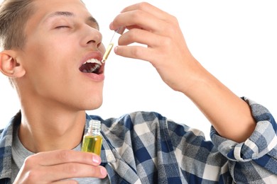 Photo of Young man taking CBD tincture indoors. Herbal extract