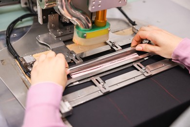 Photo of Young woman working with machine in professional workshop, closeup