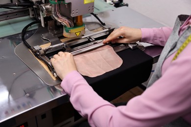 Photo of Young woman working with machine in professional workshop, closeup