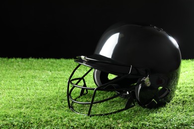 Photo of Baseball helmet on artificial grass against black background, space for text