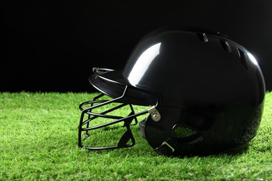 Photo of Baseball helmet on artificial grass against black background, space for text