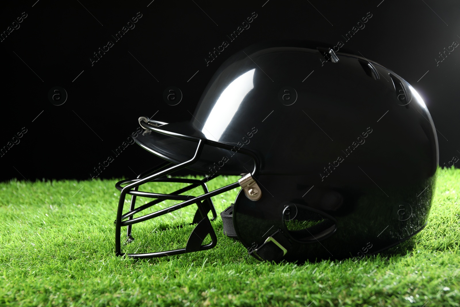 Photo of Baseball helmet on artificial grass against black background