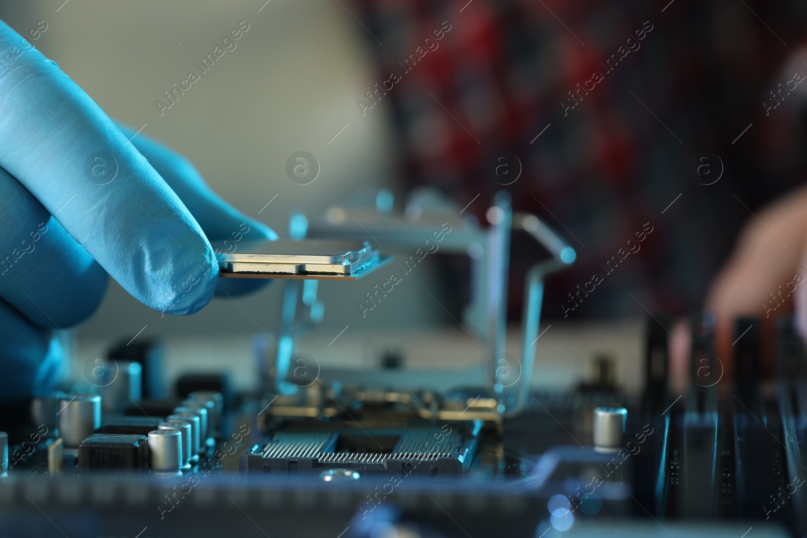 Photo of Man installing computer chip onto motherboard at table, closeup