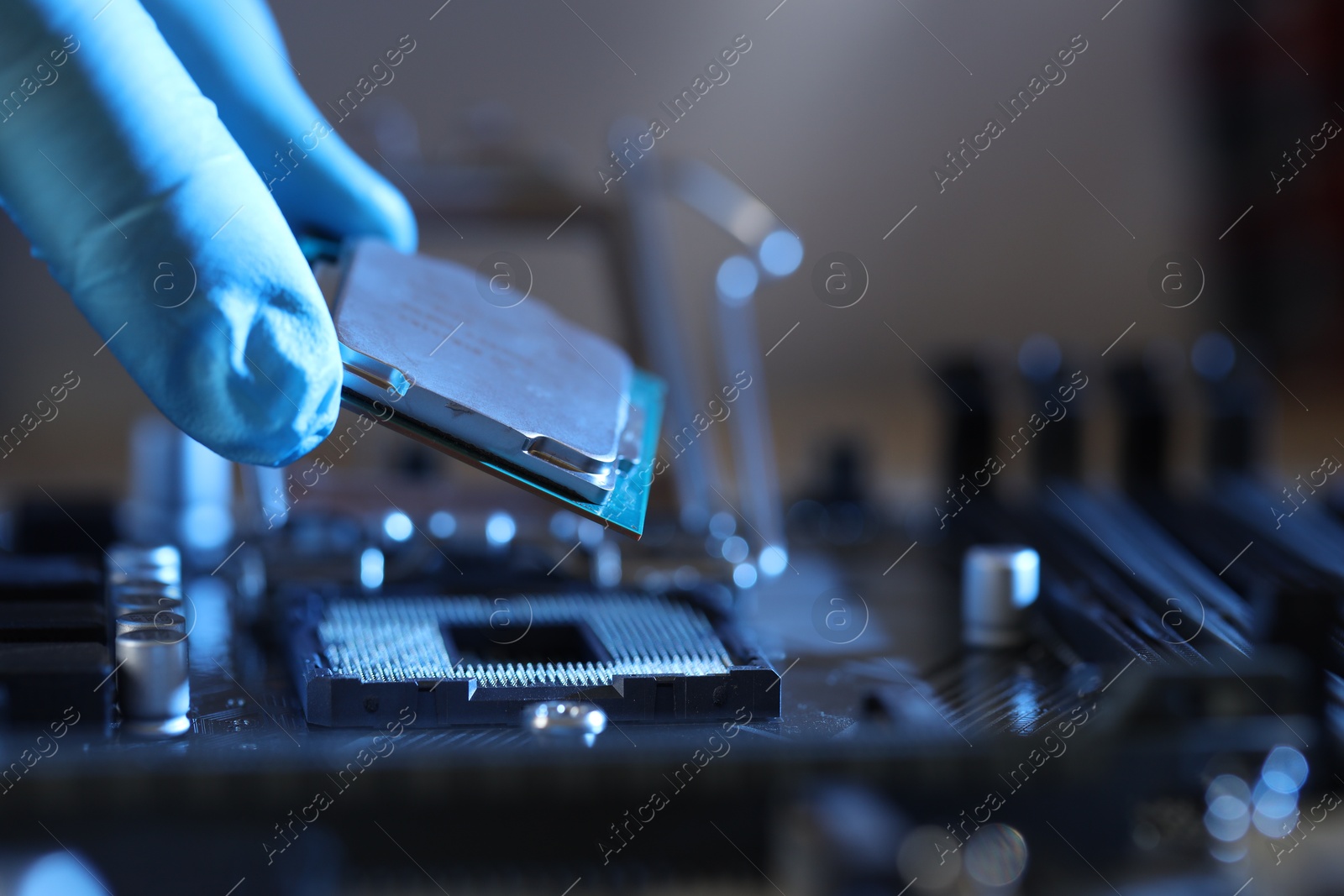 Photo of Man installing computer chip onto motherboard at table, closeup