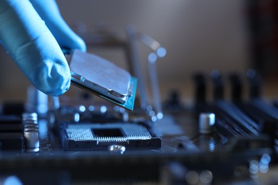 Man installing computer chip onto motherboard at table, closeup