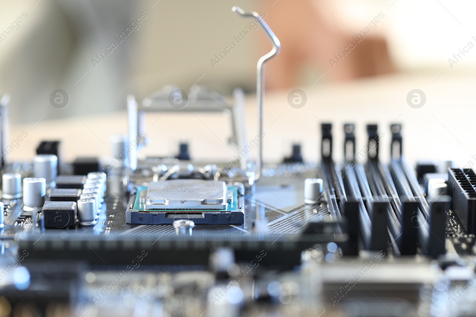 Photo of Motherboard with modern computer chip and other components on table, closeup