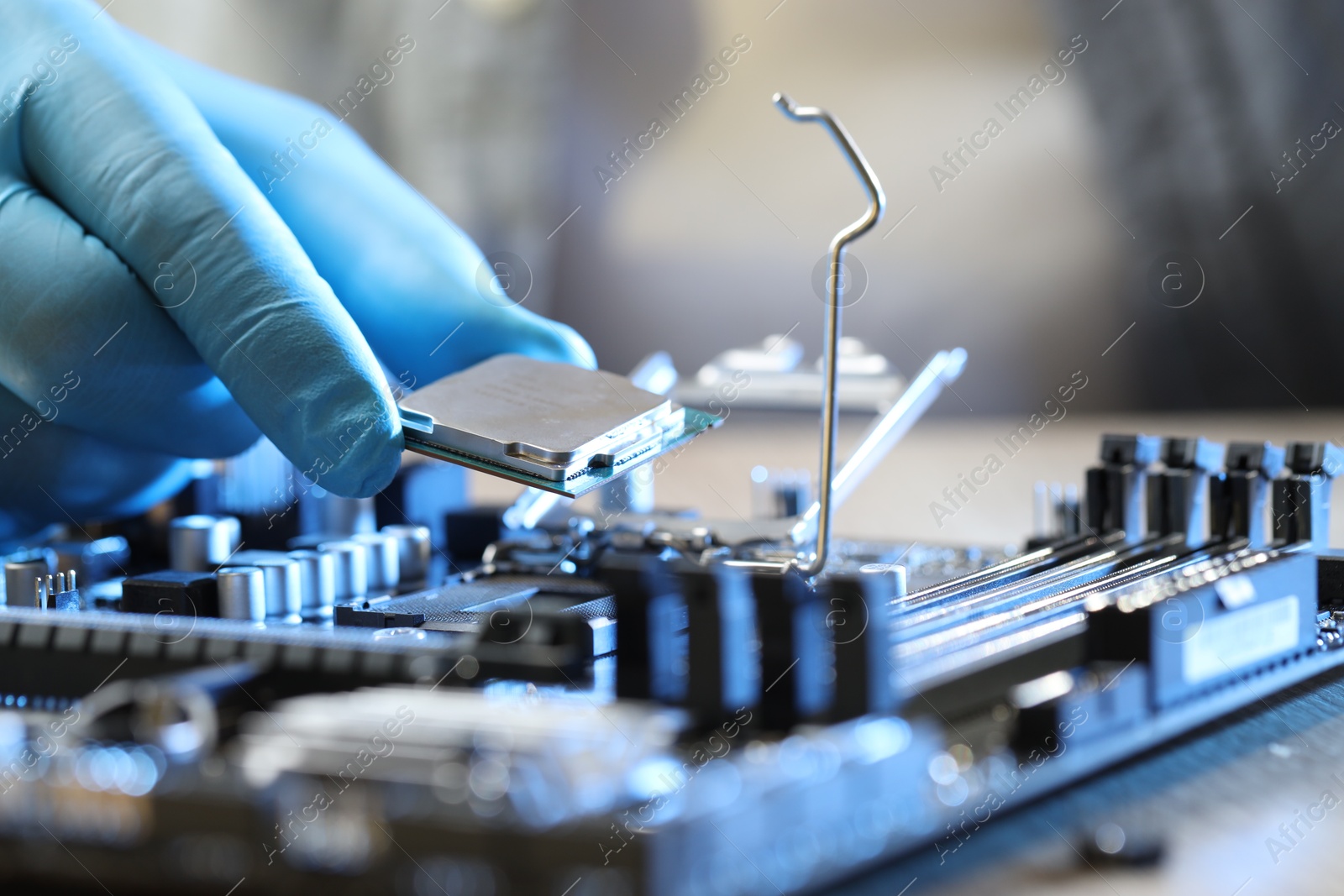 Photo of Man installing computer chip onto motherboard at wooden table, closeup