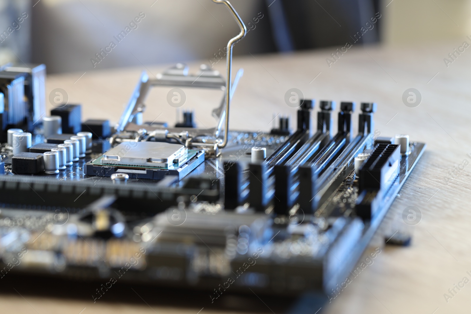 Photo of Motherboard with modern computer chip and other components on wooden table, closeup