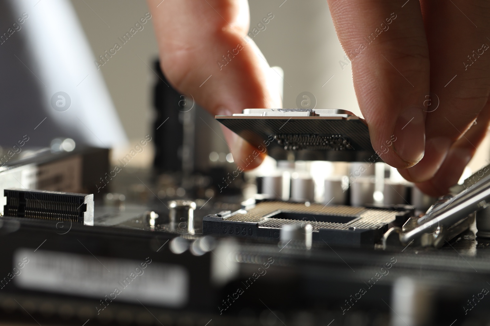 Photo of Man installing computer chip onto motherboard at table, closeup