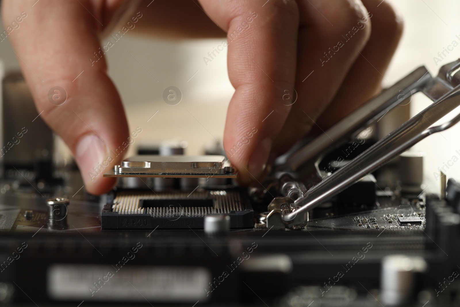 Photo of Man installing computer chip onto motherboard at table, closeup